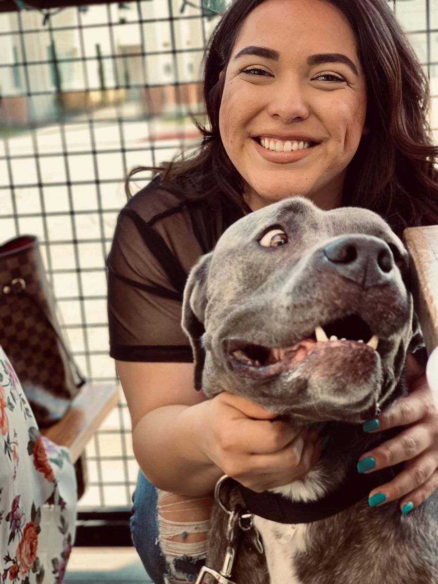 Candace smiling with a happy gray pup